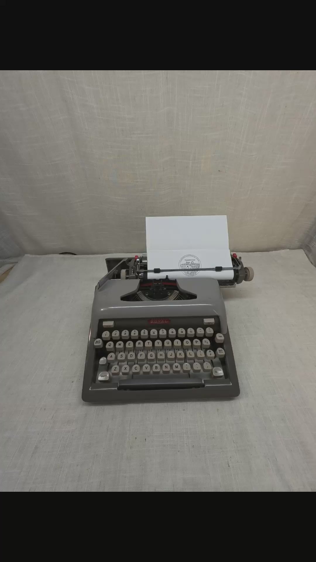 A person's hands typing on a grey typewriter.