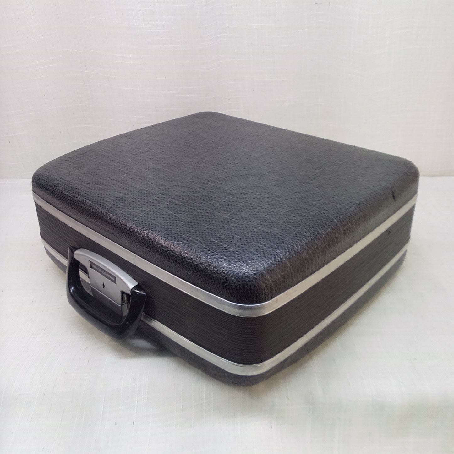 Black hard-shell typewriter case on a white background.