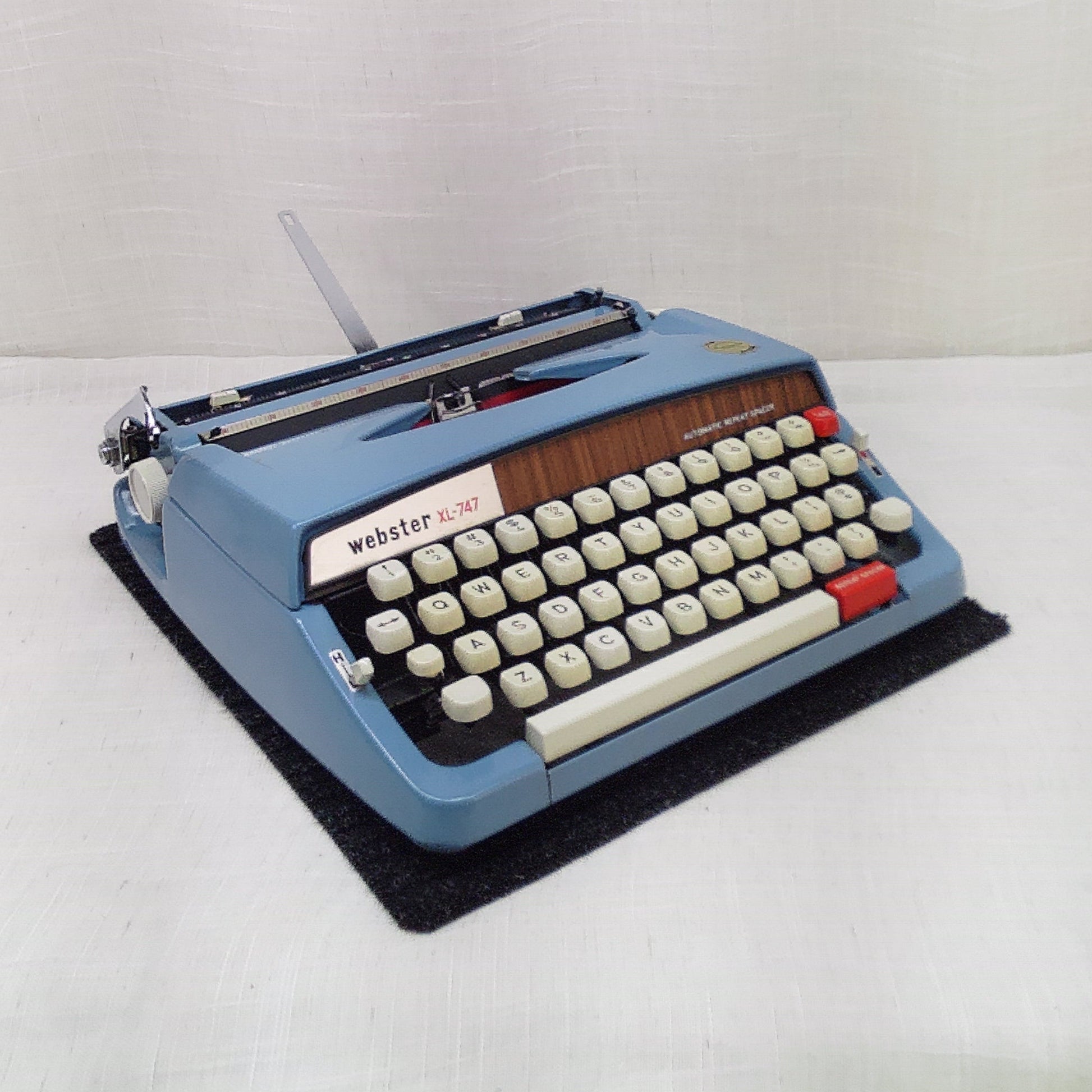 Vintage blue typewriter on a white surface with a plain background