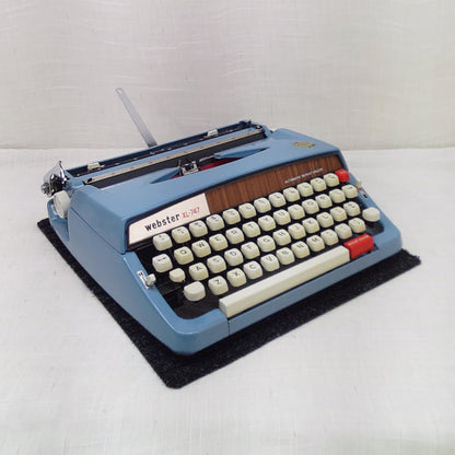 Vintage blue typewriter on a white surface with a plain background